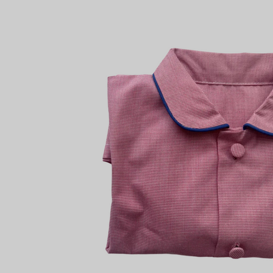 Folded pink checkered fabric with blue trim on a light gray background